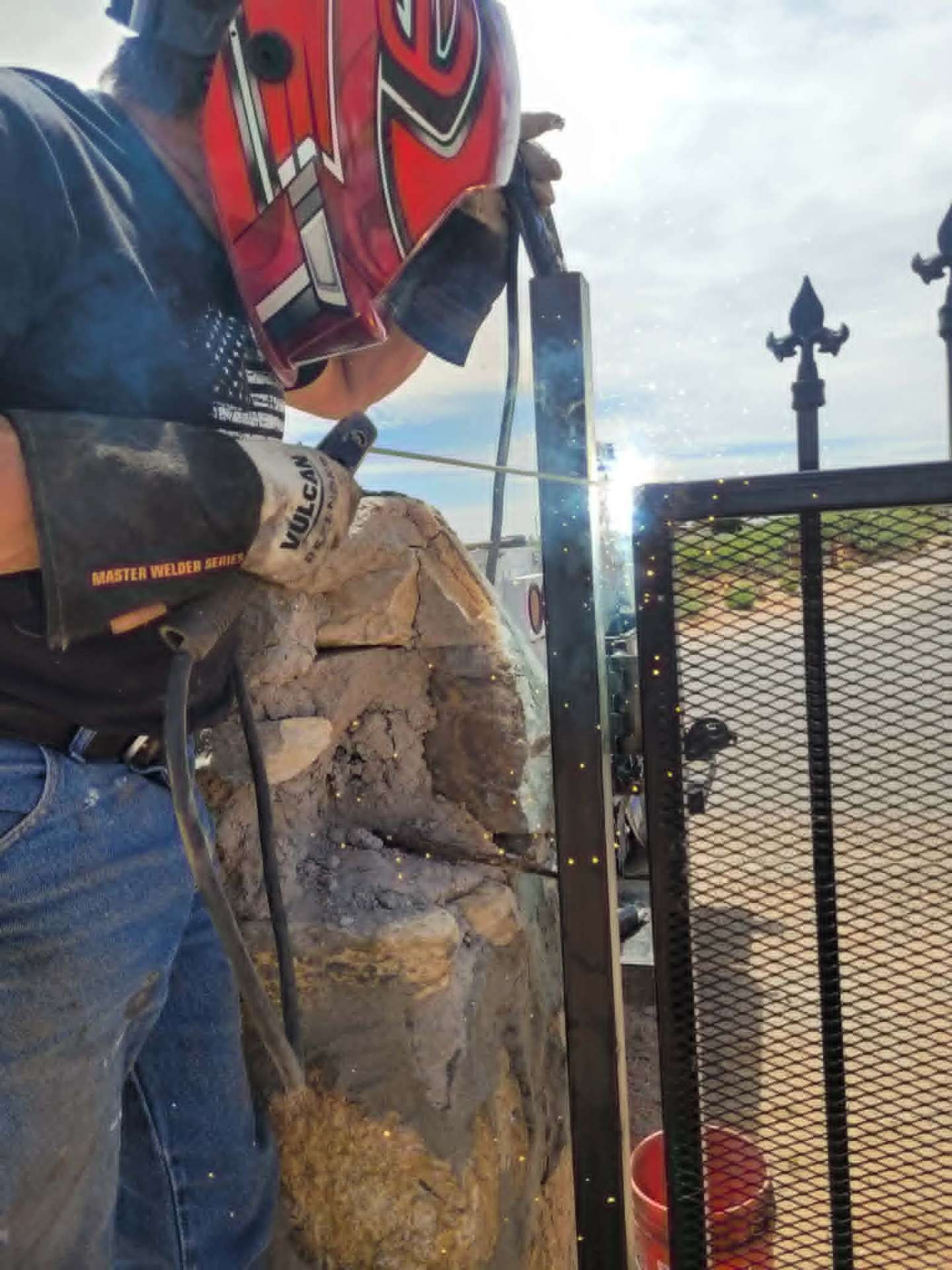 On-site welding of a wrought iron gate to a stone column